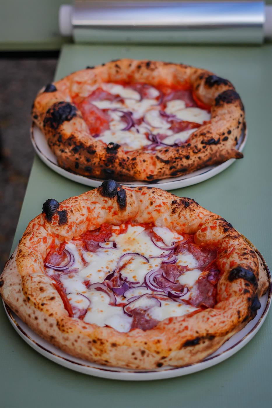 Dvě neapolské pizzy se salámem a červenou cibulí