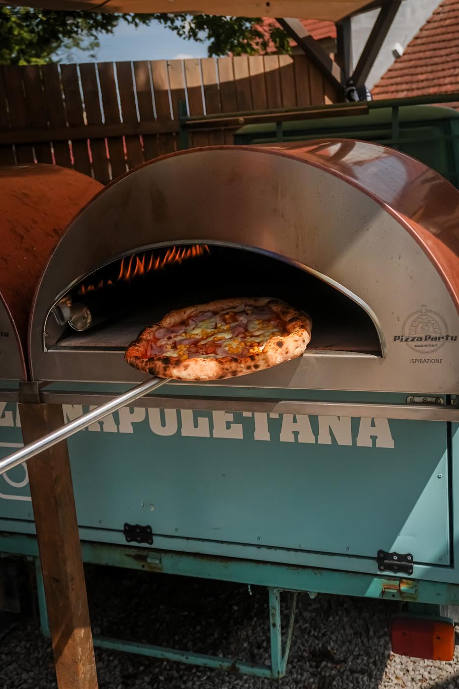 Pizza vyjíždí z pece na tyrkysovém vozítku