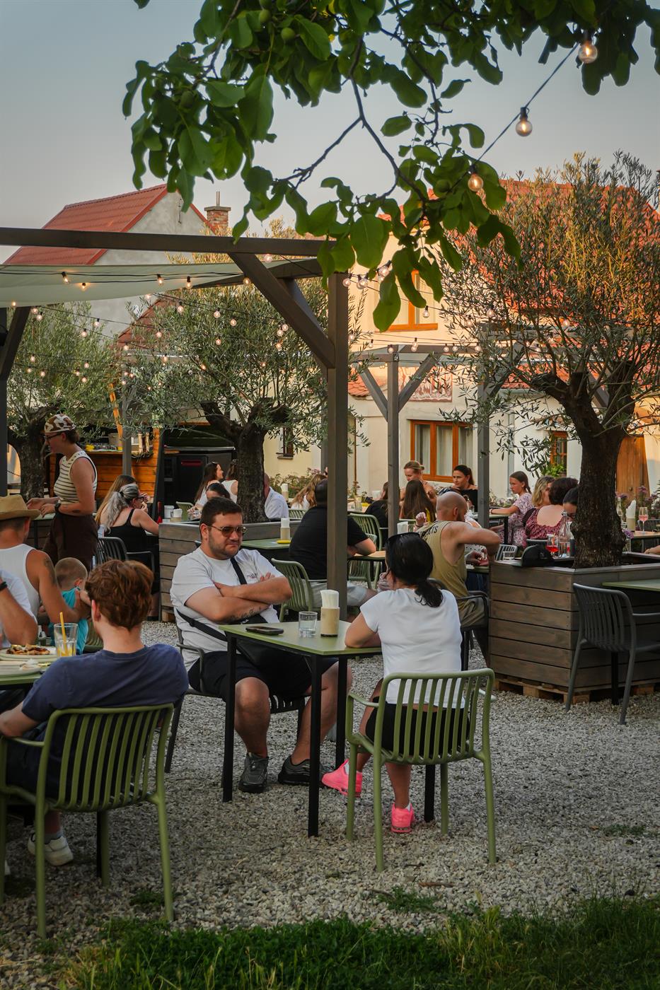 Plná zahrada Per La Pizza za soumraku pod olivovníky